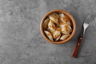 Photo of Delicious cooked dumplings with fried onion on grey table, flat lay. Space for text