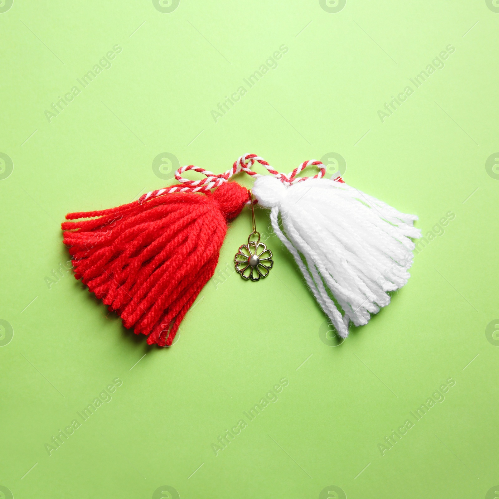 Photo of Traditional martisor on green background, top view. Beginning of spring celebration