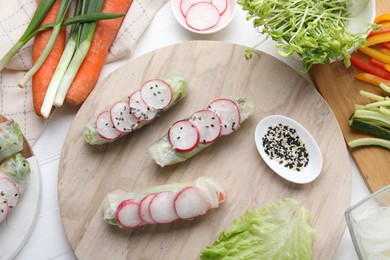 Photo of Delicious spring rolls and ingredients on white wooden table, top view