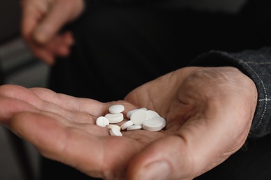 Senior man holding pills in his hand, closeup
