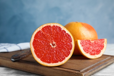 Photo of Fresh tasty grapefruits on board against color background