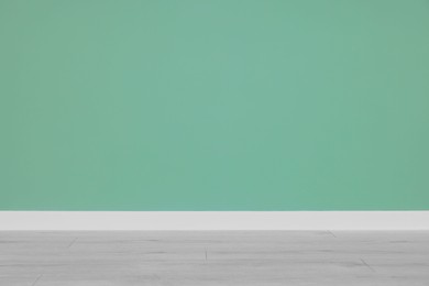 Photo of Beautiful light green wall and wooden floor in clean empty room
