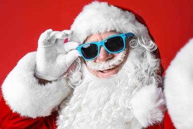 Photo of Authentic Santa Claus wearing sunglasses on color background