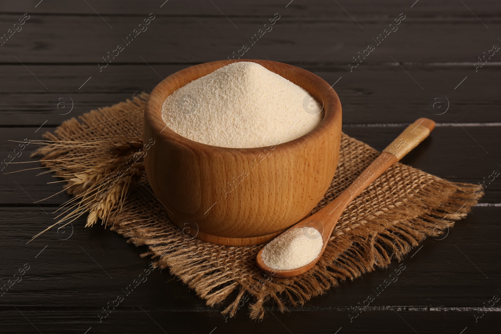 Photo of Fresh semolina and spikelets on black wooden table