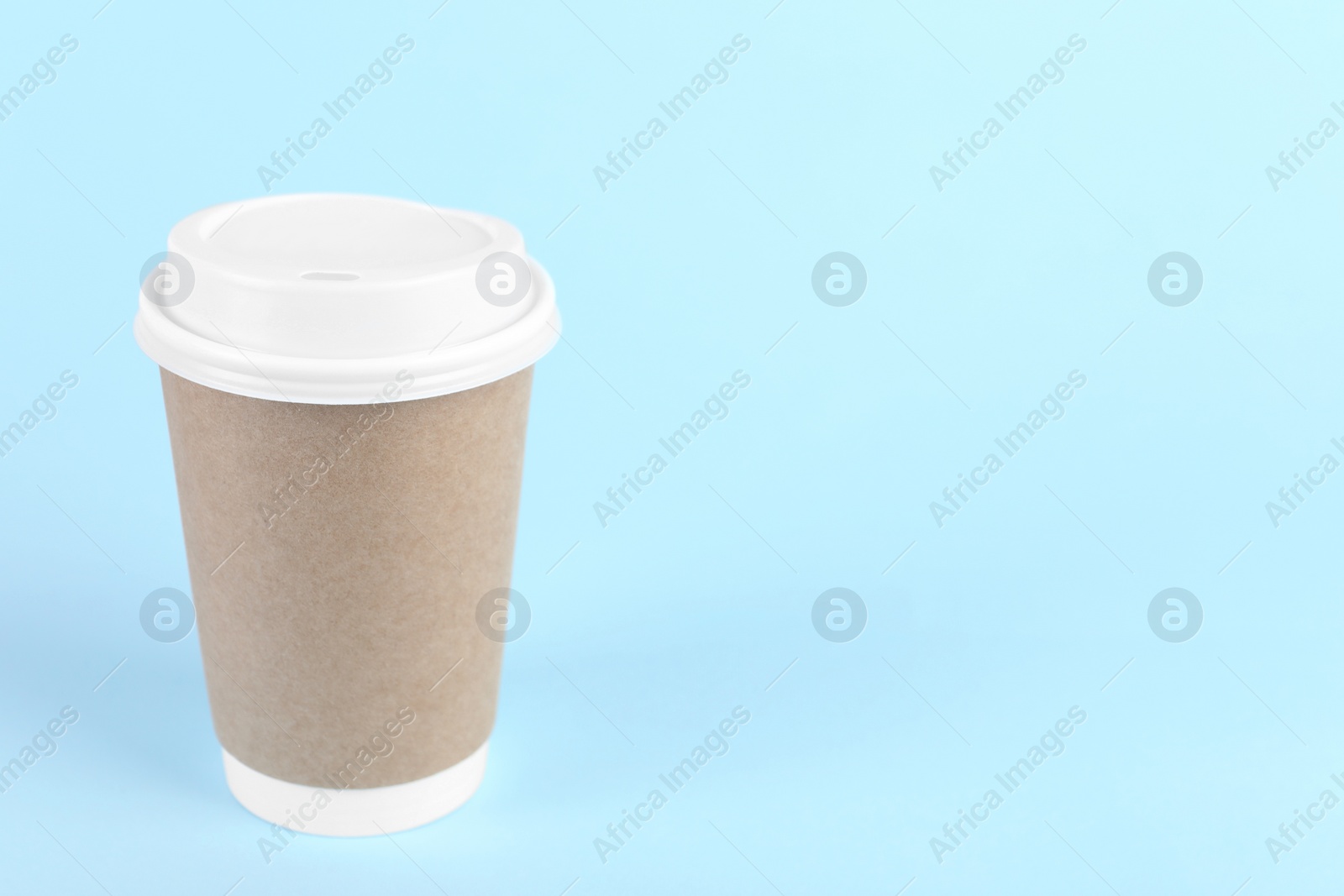 Photo of Paper cup with plastic lid on light blue background, space for text. Coffee to go