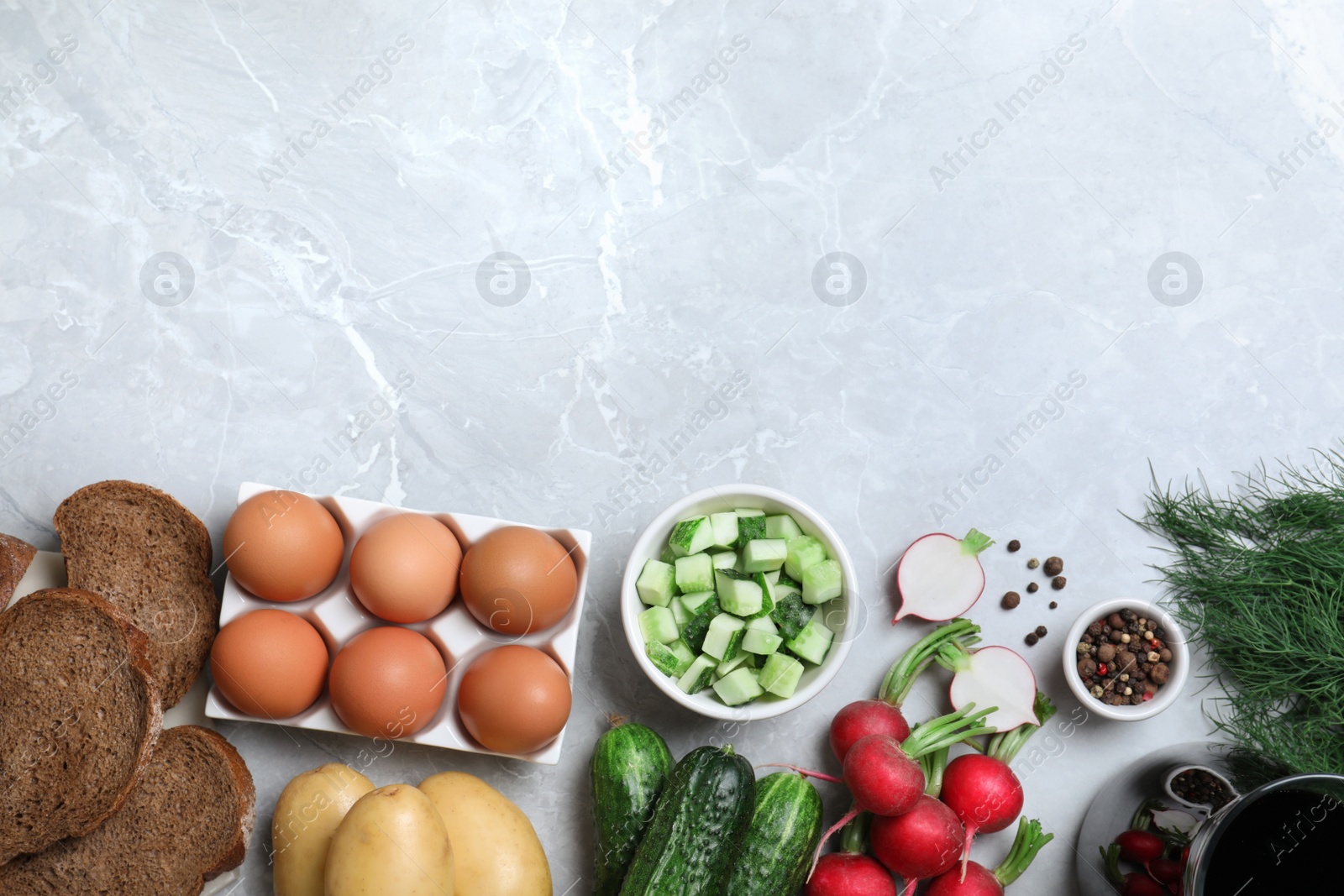 Photo of Flat lay composition with kvass and other okroshka ingredients on grey table, space for text. Traditional Russian summer soup