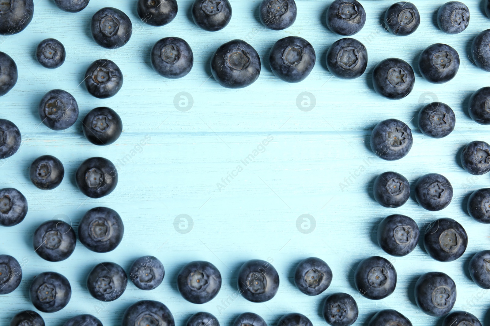 Photo of Frame made with fresh blueberries on wooden table, top view. Space for text