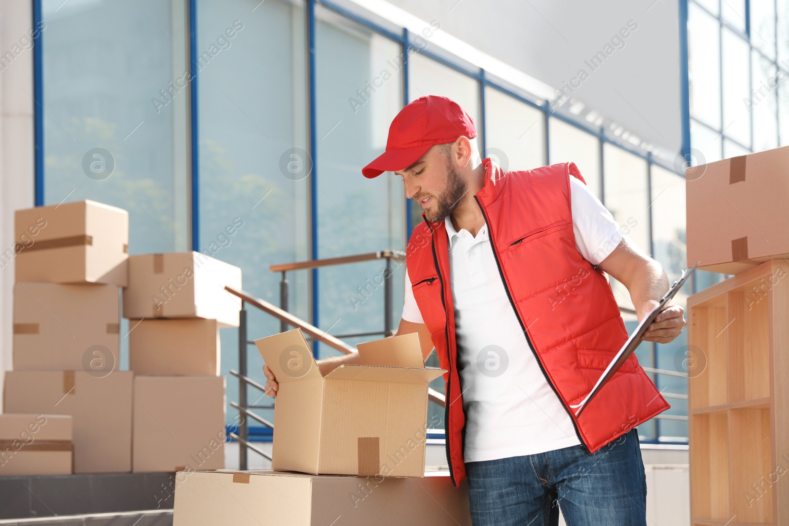 Photo of Male mover with clipboard and boxes outdoors on sunny day