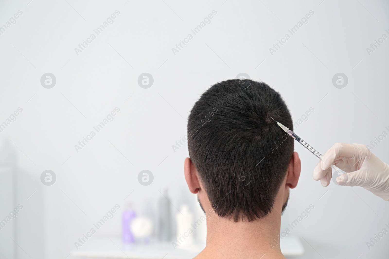 Photo of Man with hair loss problem receiving injection in salon. Space for text