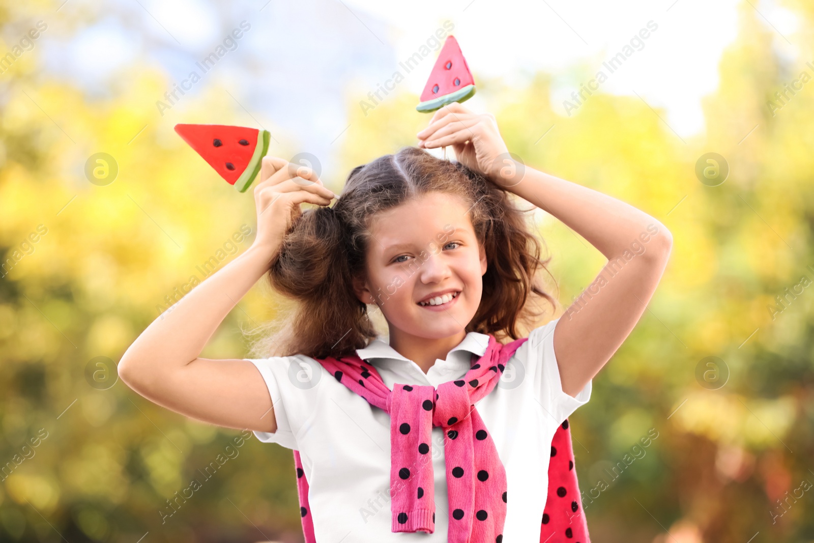 Photo of Cute little girl with tasty candies outdoors