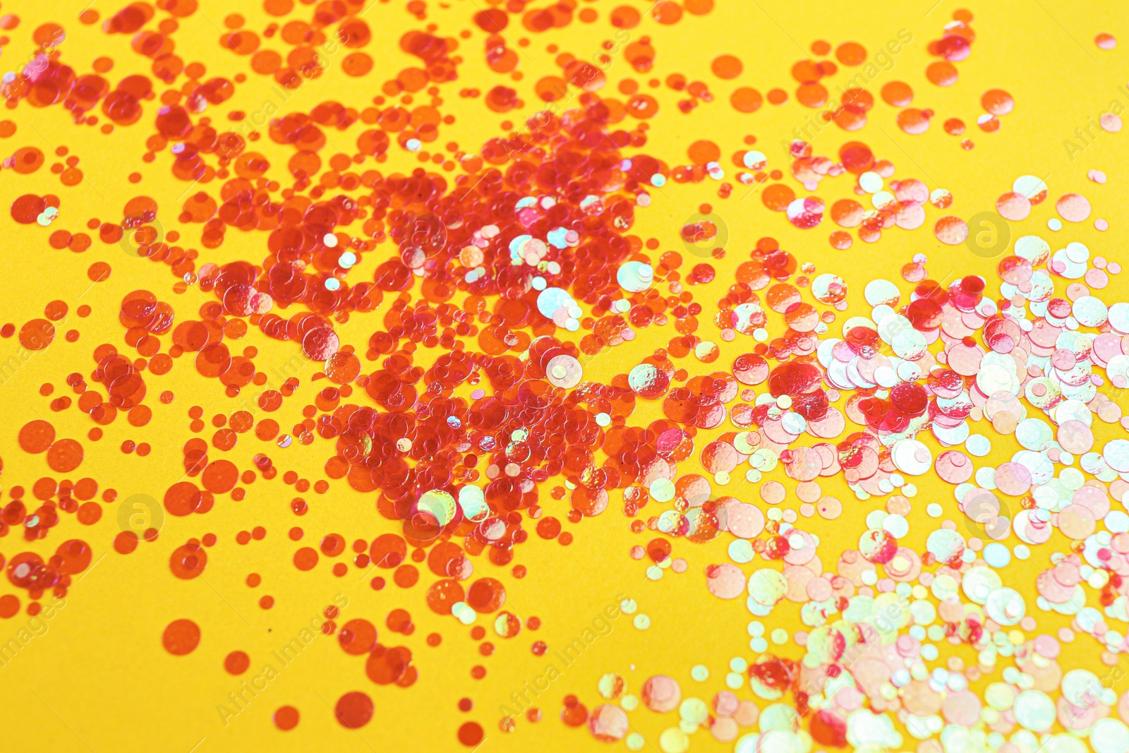 Photo of Shiny bright red glitter on yellow background
