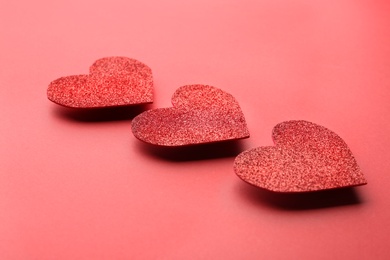 Photo of Red shiny paper hearts on color background