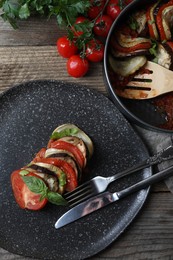 Photo of Delicious ratatouille served with basil on wooden table, flat lay