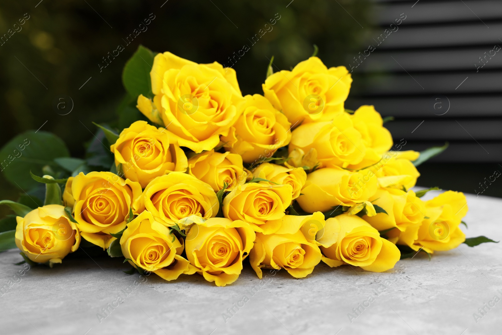 Photo of Beautiful bouquet of yellow roses on light table outdoors