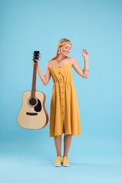 Photo of Happy hippie woman with guitar on light blue background