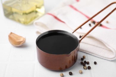 Photo of Metal small saucepan with balsamic vinegar and ingredients on white table