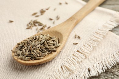 Photo of Spoon with caraway seeds and napkin on table, closeup