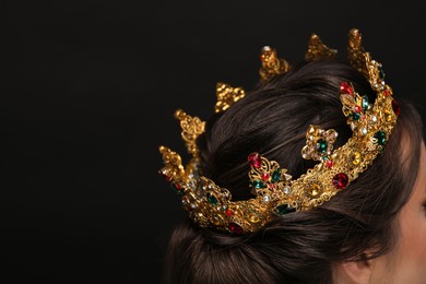 Photo of Woman wearing luxurious crown on black background, closeup. Space for text