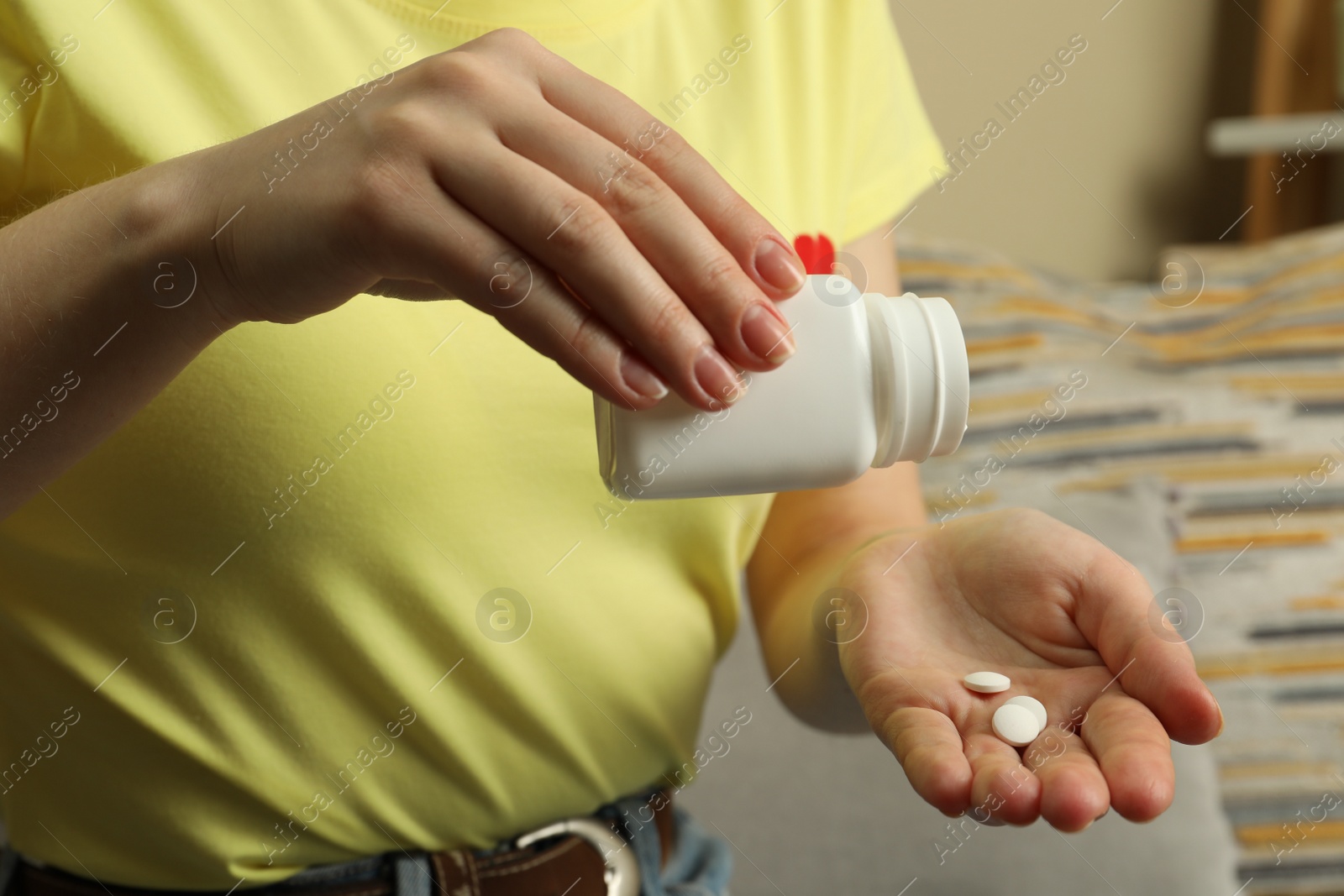 Photo of Woman pouring pills from bottle indoors, closeup. Menopause concept