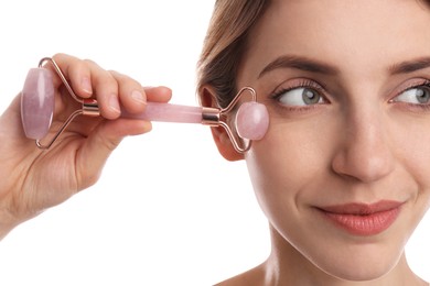 Young woman using natural rose quartz face roller on white background, closeup