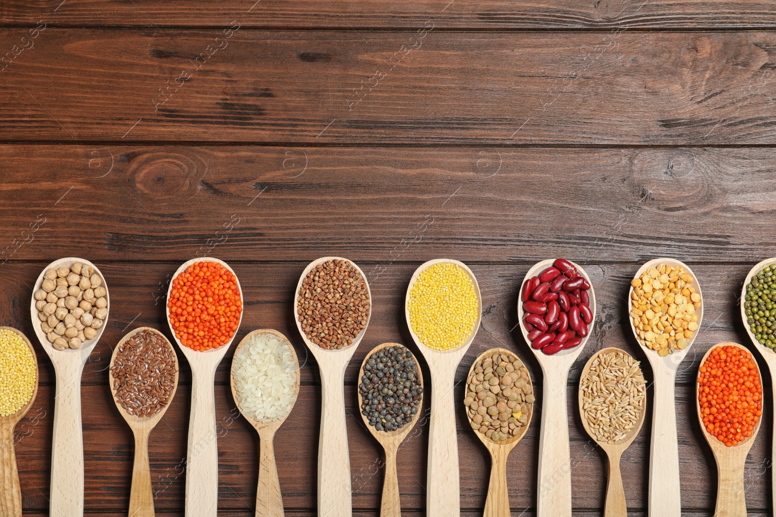 Photo of Flat lay composition with different types of legumes and cereals on wooden table, space for text. Organic grains