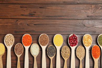 Photo of Flat lay composition with different types of legumes and cereals on wooden table, space for text. Organic grains