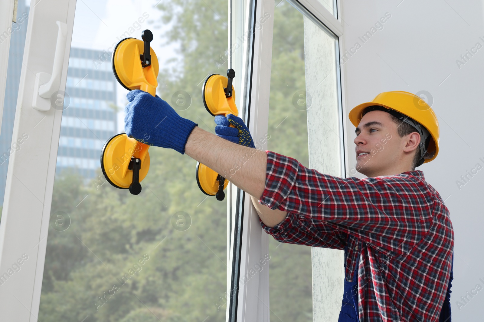 Photo of Worker using suction lifters during plastic window installation indoors