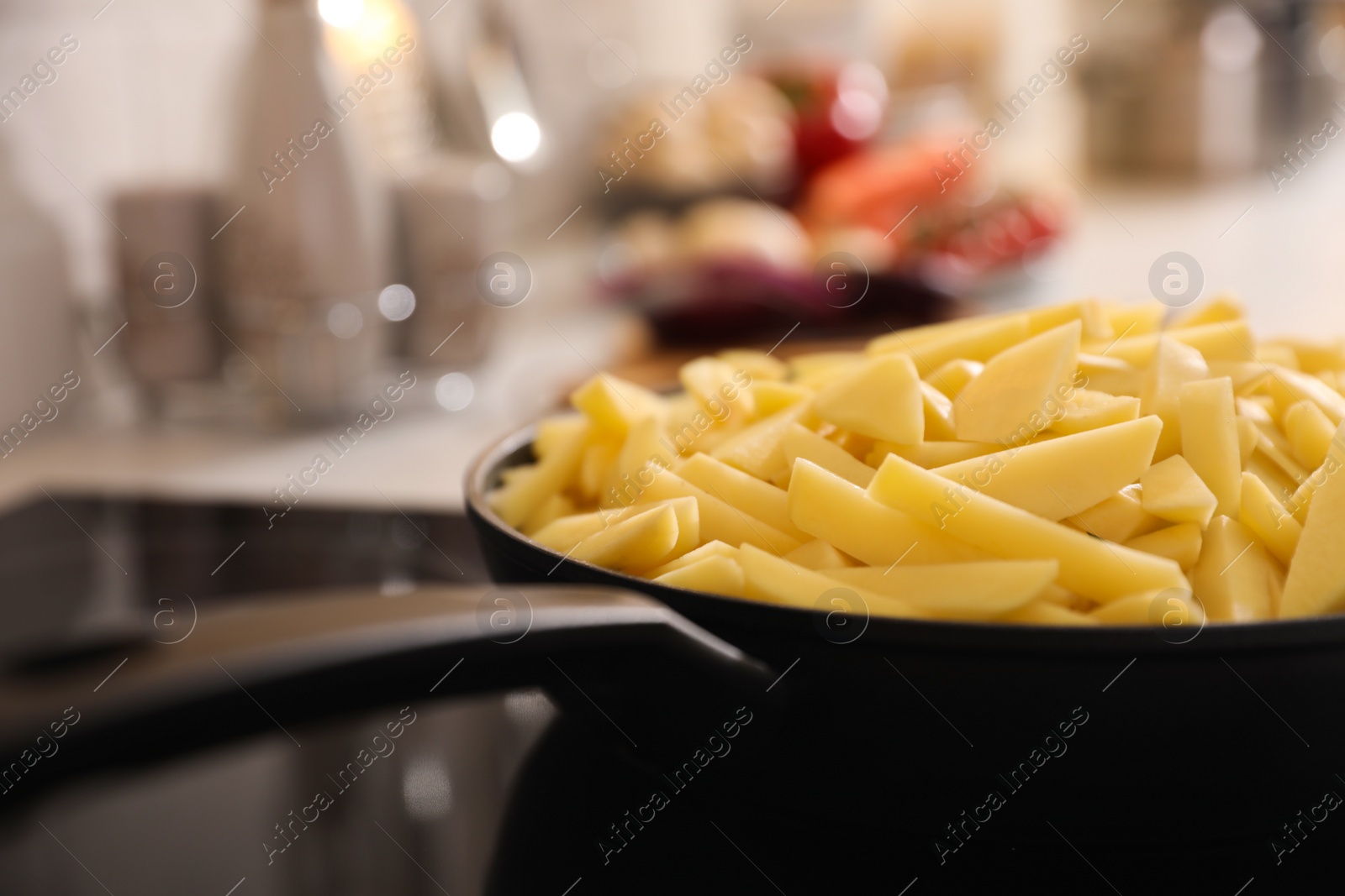 Photo of Frying pan with cut raw potatoes on stove, closeup. Space for text
