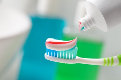 Applying toothpaste on brush against blurred background, closeup