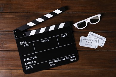 Clapperboard, movie tickets and 3D glasses on wooden table, flat lay