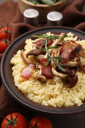 Photo of Tasty couscous with mushrooms and bacon in bowl on table, closeup