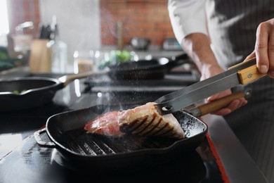 Photo of Professional chef cooking meat on stove in restaurant kitchen, closeup