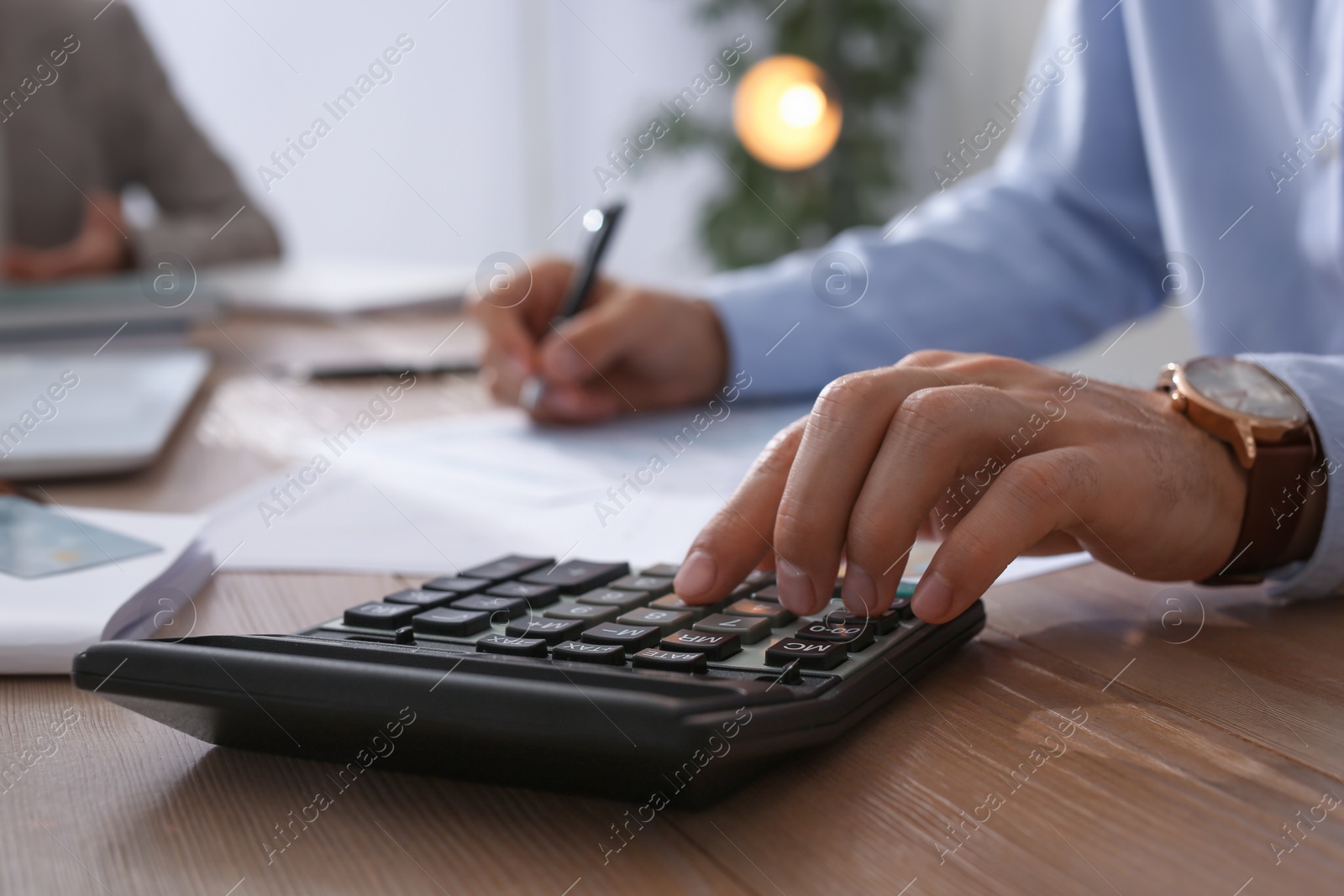 Photo of Tax accountant with calculator working at table in office, closeup