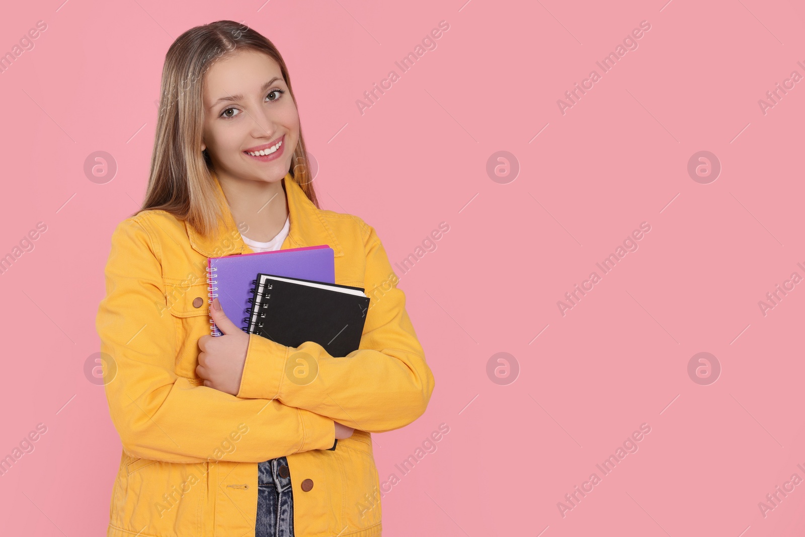 Photo of Teenage girl with notebooks on pink background. Space for text