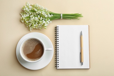 Flat lay composition with notebook, lily of the valley bouquet and coffee on color background