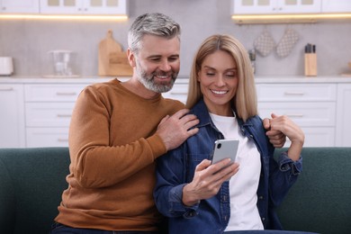 Photo of Happy affectionate couple with smartphone phone spending time together at home. Romantic date