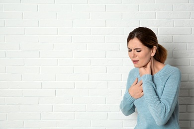 Photo of Woman suffering from cough near brick wall. Space for text