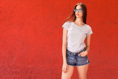 Photo of Young woman wearing gray t-shirt near color wall on street