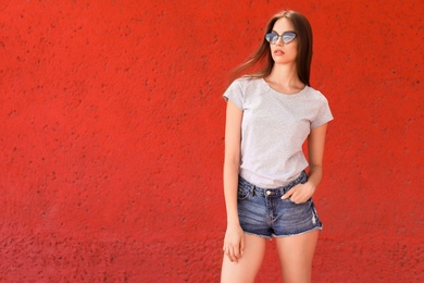 Young woman wearing gray t-shirt near color wall on street