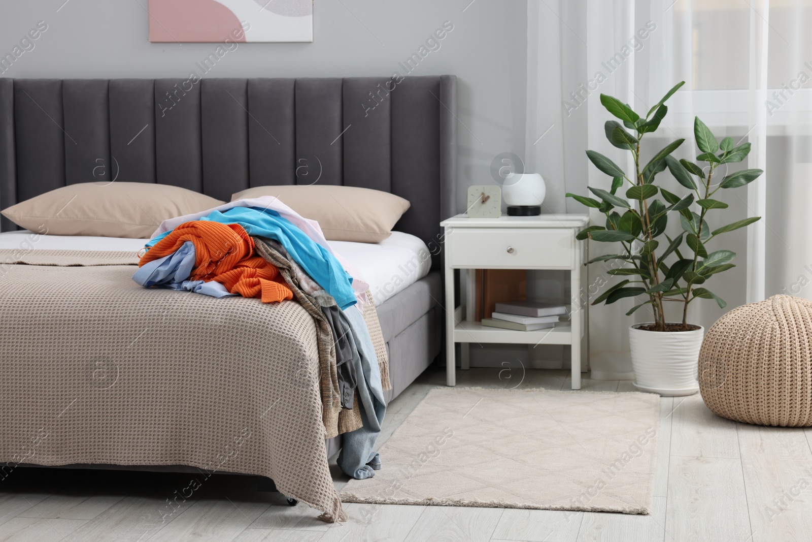 Photo of Pile of different clothes on bed at home