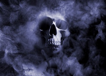 Image of Scary skull emerging from smoke in darkness