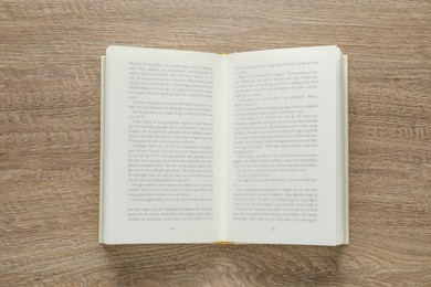 Open book on wooden table, top view