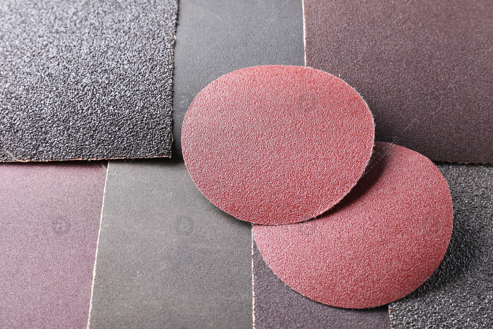 Photo of Many sheets of sandpaper as background, closeup