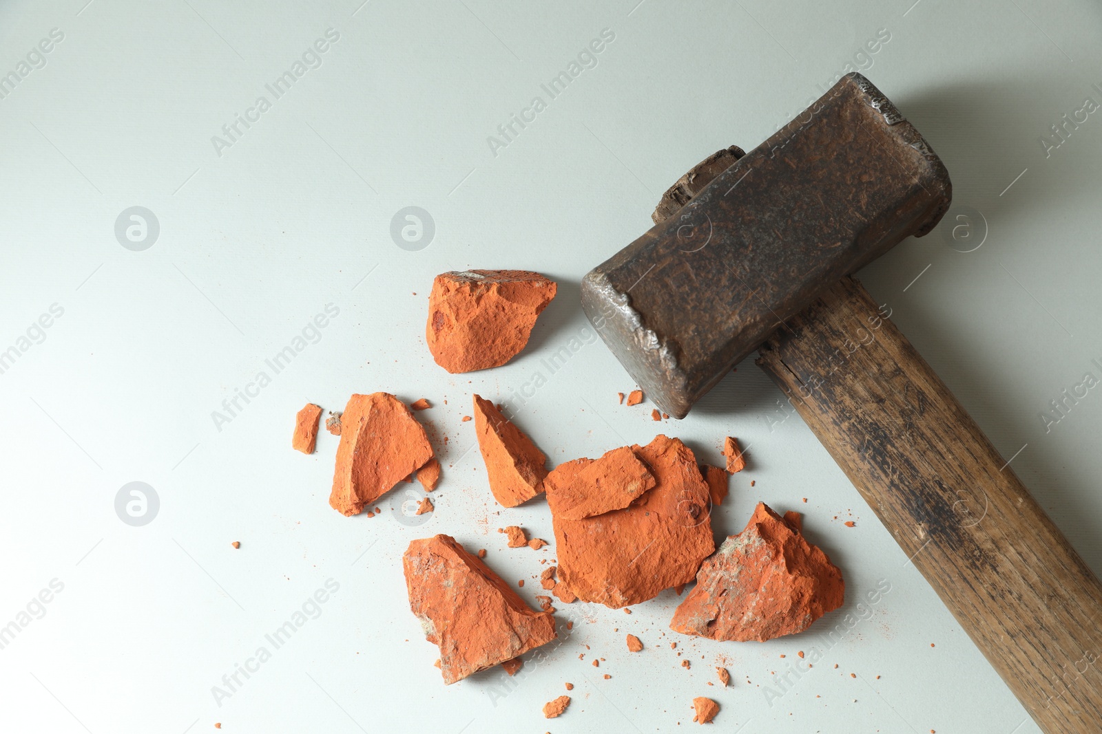 Photo of Sledgehammer and pieces of broken brick on grey background, top view. Space for text