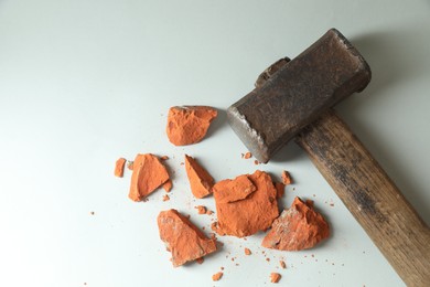 Sledgehammer and pieces of broken brick on grey background, top view. Space for text