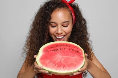 Photo of Beautiful young African American woman with half of watermelon on grey background