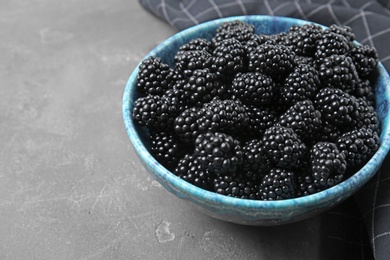 Bowl of ripe blackberries on grey table, space for text