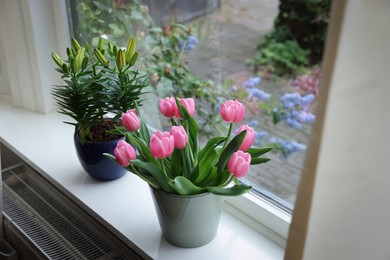 Beautiful bouquet with pink tulips and potted lily on white window sill indoors