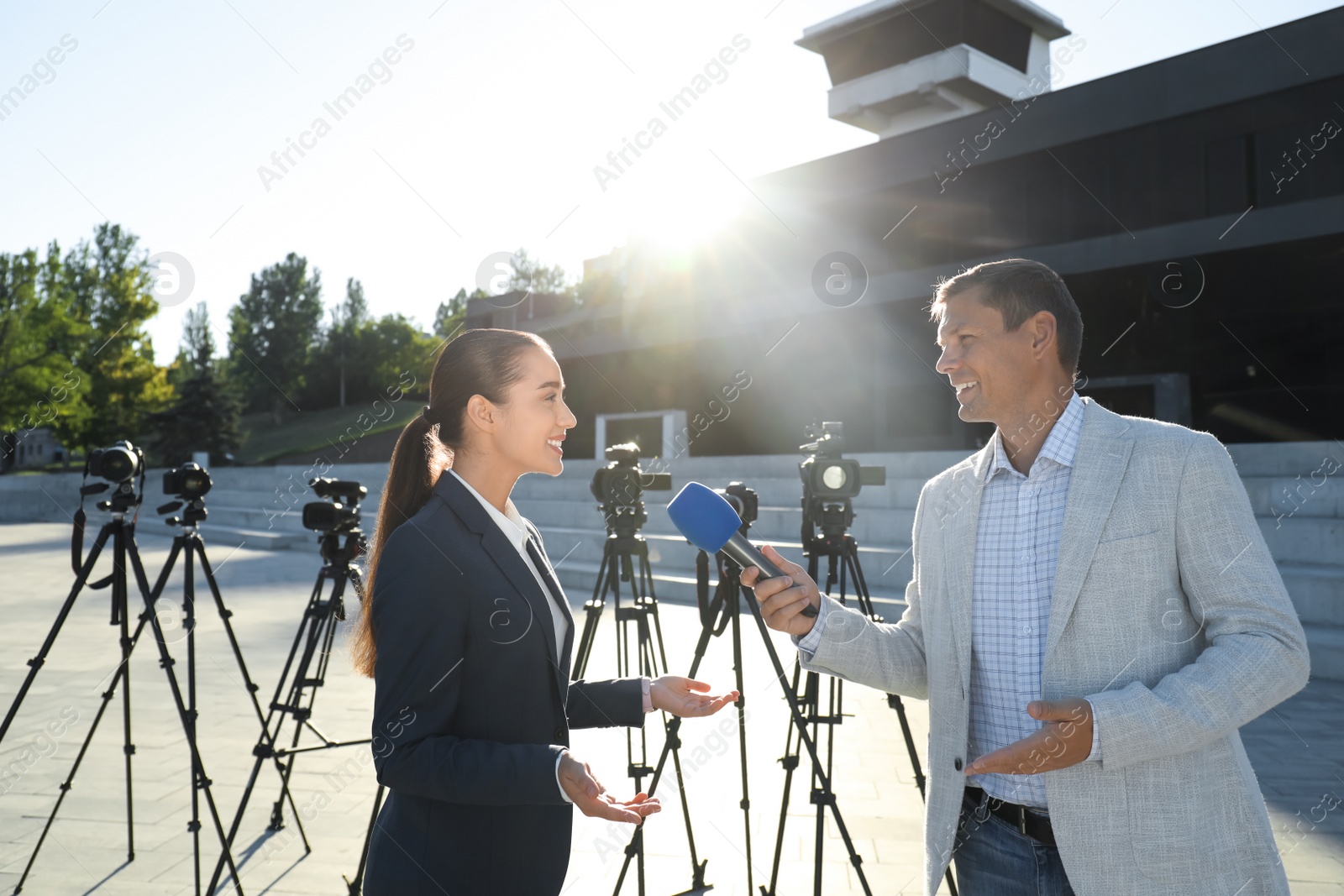 Photo of Professional journalist interviewing young woman on city street