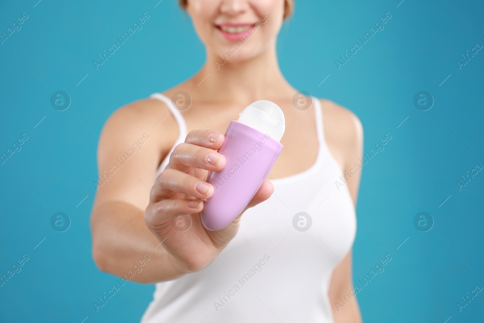 Photo of Young woman holding deodorant on teal background, closeup. Mockup for design